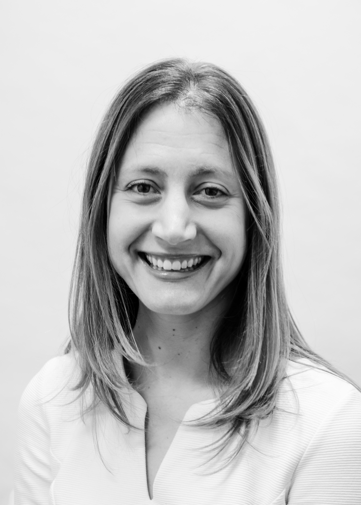 Black and white head and shoulders picture of a smiling woman with hair just below her shoulders.