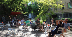 A photograph of the museum terrace area, with people spread out at small tables enjoying the sun and drinks