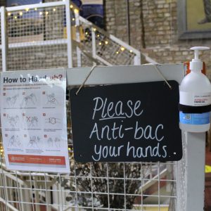 Sign saying "please Anti-bac your hands", with hand sanitiser on one side and a "How to Hand rub" guidance sign on the other.