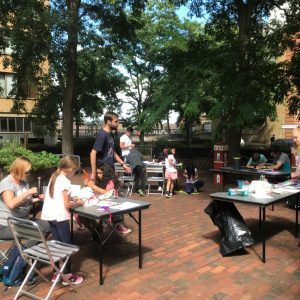 A view of the Brunel Museum courtyard with socially-distanced tables and families having fun making hats from craft supplies.
