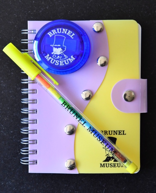 Various stationery items: a popacrayon, a notebook, and a pencil sharpener.
