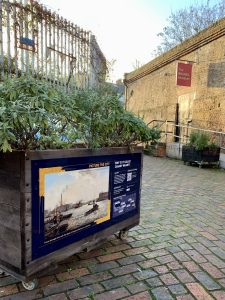 Image shows a planter on a piazza in front of an open door with a sign that says Brunel Museum