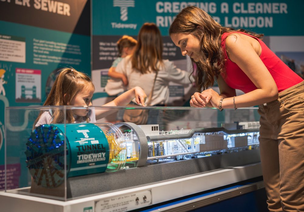Image shows a teaanger and a child looking at a Tideway Super Serew Tunneling Boring Machine model, part of the Brunel Museum's Tunnelling Today exhibition