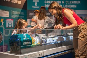 Image shows a teaanger and a child looking at a Tideway Super Serew Tunneling Boring Machine model, part of the Brunel Museum's Tunnelling Today exhibition