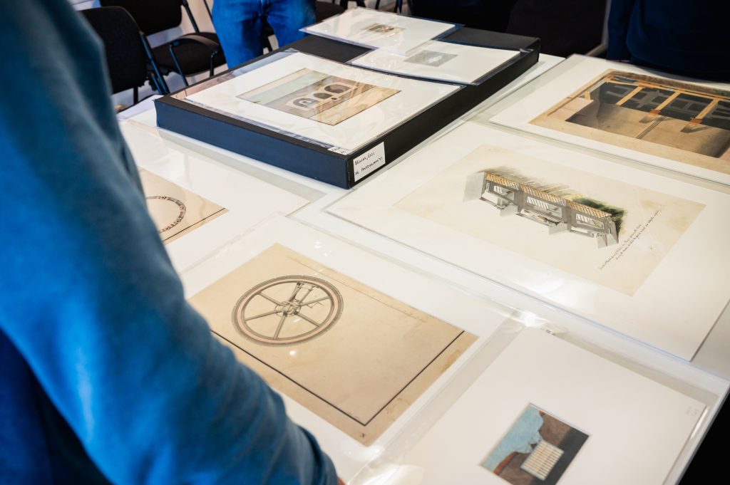 A collection of historical technical drawings are laid out on a table.