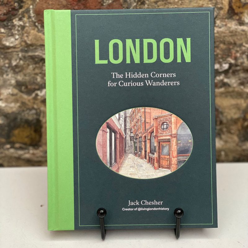 Image showing the book The Hidden Corners on a book stand, and a brick wall on the background